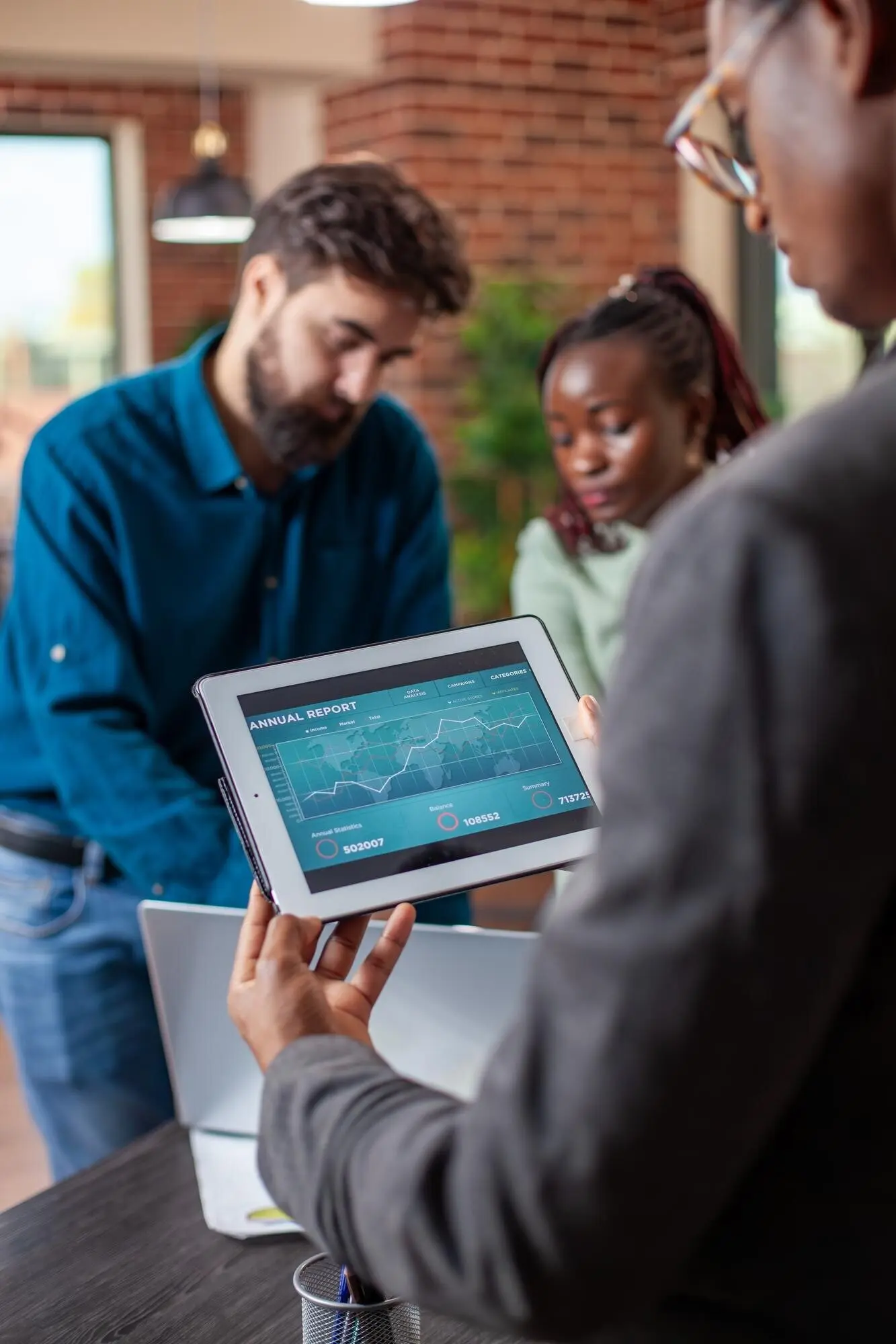 Чернокожий менеджер оценивает отчёты на планшете.