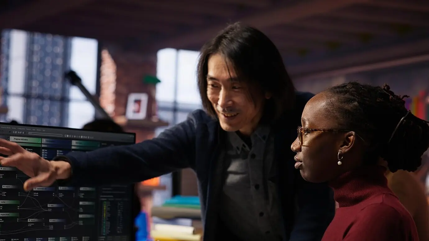 Старший руководитель команды помогает сотруднику в агентстве по разработке программного обеспечения на основе искусственного интеллекта.